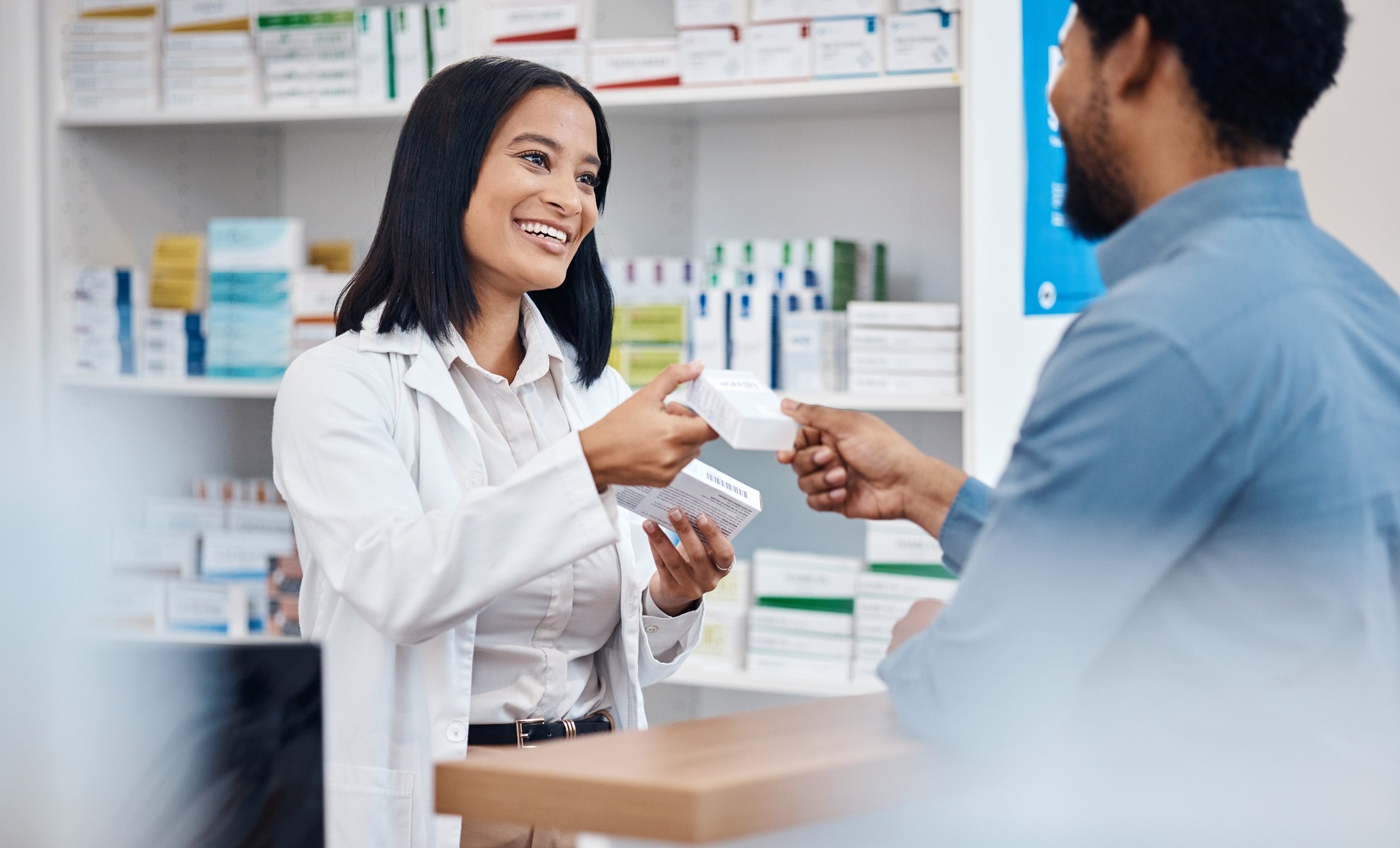 a patient is picking up a box of medication from a pharmacist at a pharmacy counter
