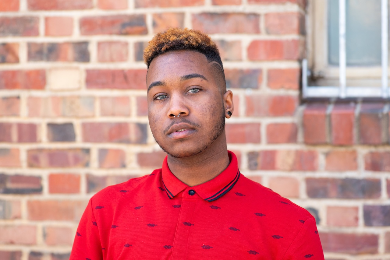 An African American trans man wearing a red polo