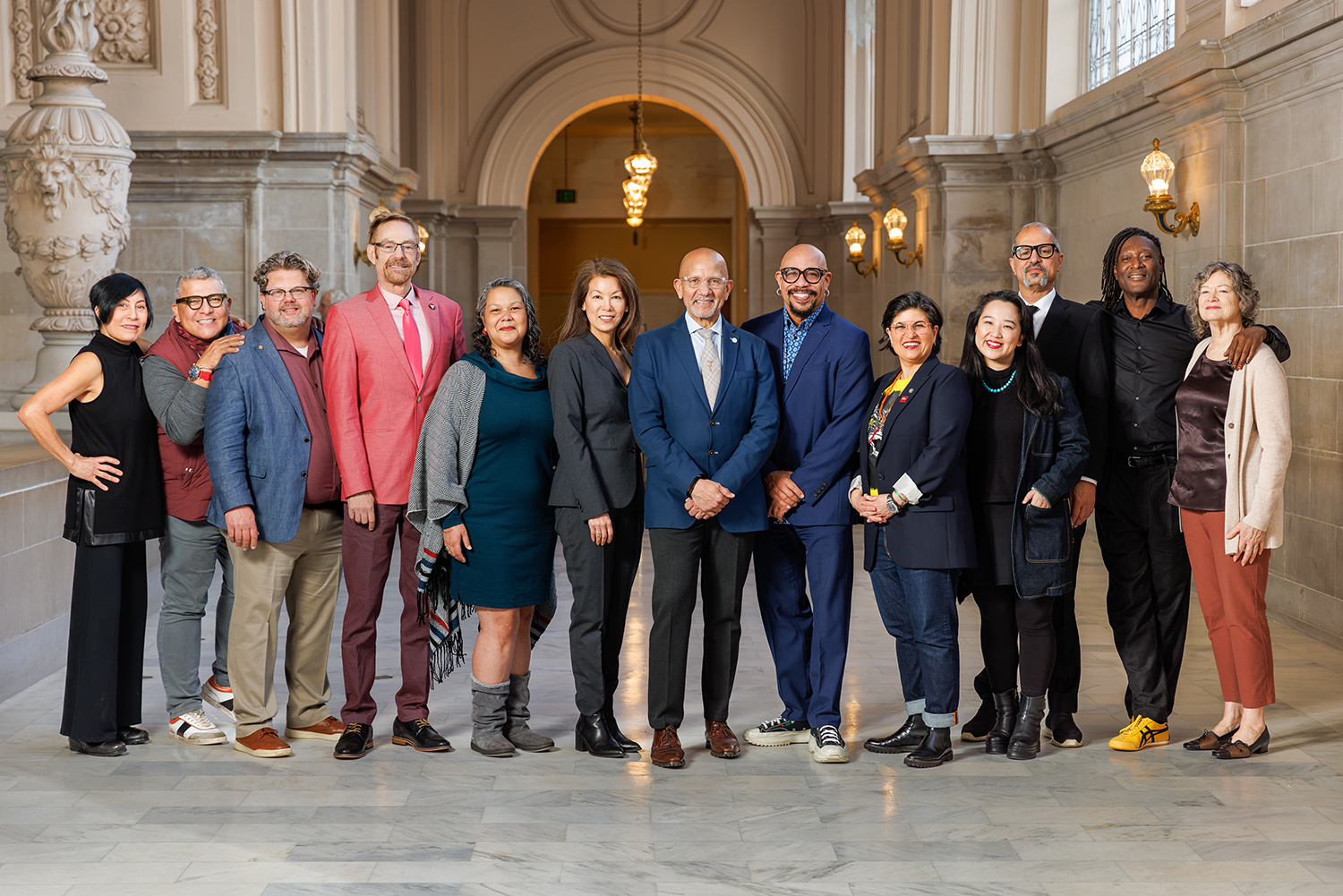 Group Photo of thirteen commissioners and the Director of Cultural Affairs standing in a line next to one another at City Hall, smiling and facing the camera.