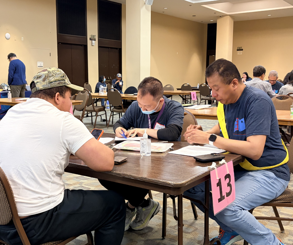 SFPCI volunteers help a participant fill out their citizenship application paperwork at a workshop setting