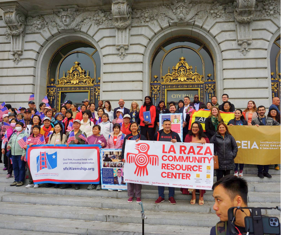 A crowd of community and City leaders stand on the steps of San Francisco City hall celebrating Citizenship Day