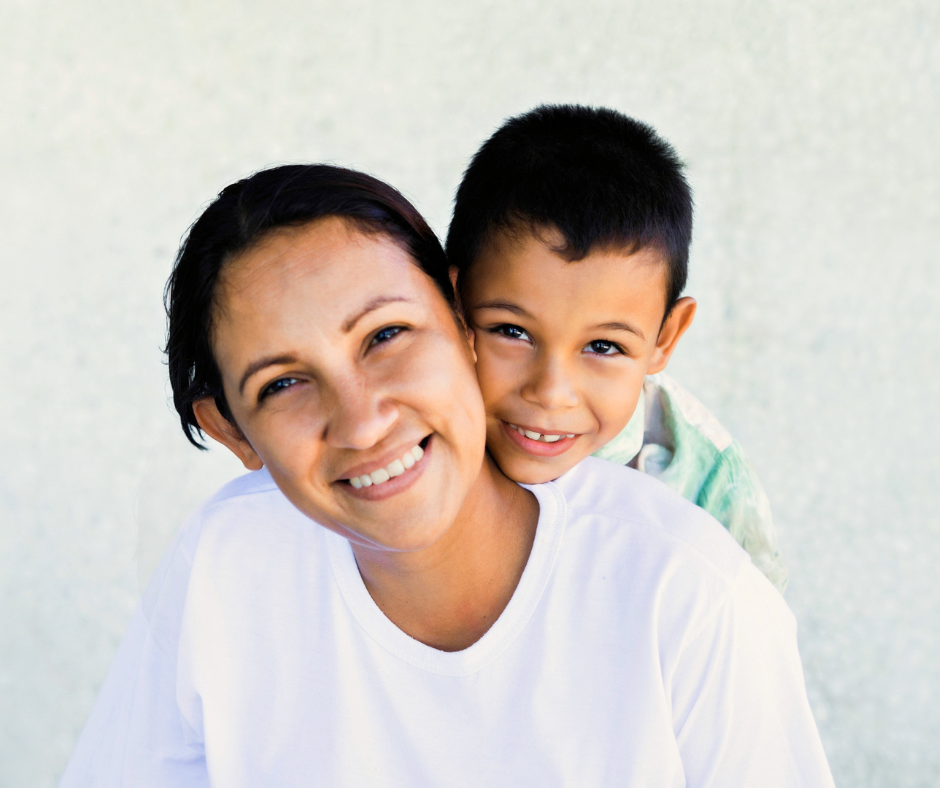 Mother and young son smile at camera with white background