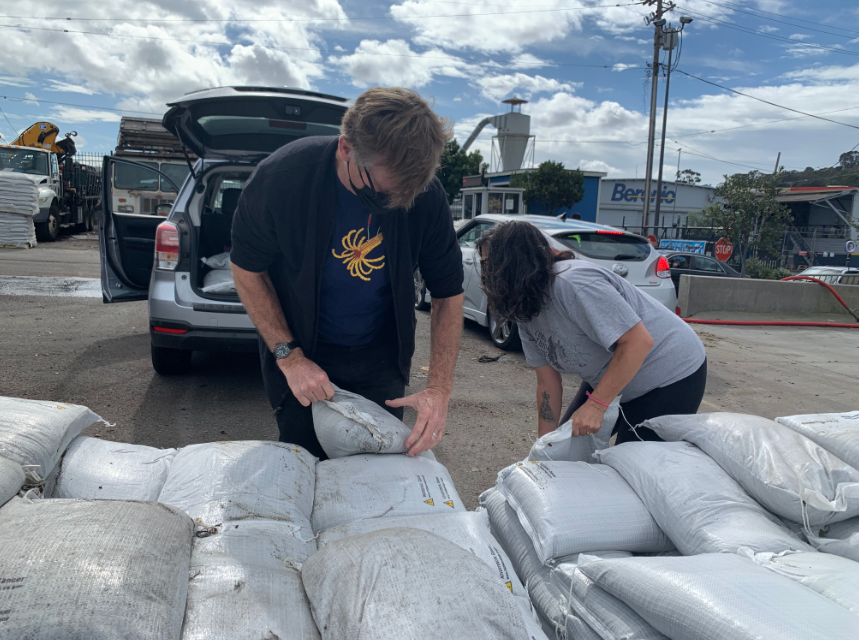 two people lift sand bags from a truck