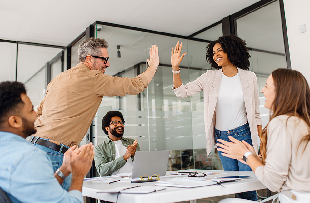 Diverse group of professionals in an office celebrates success with a high-five stock photo