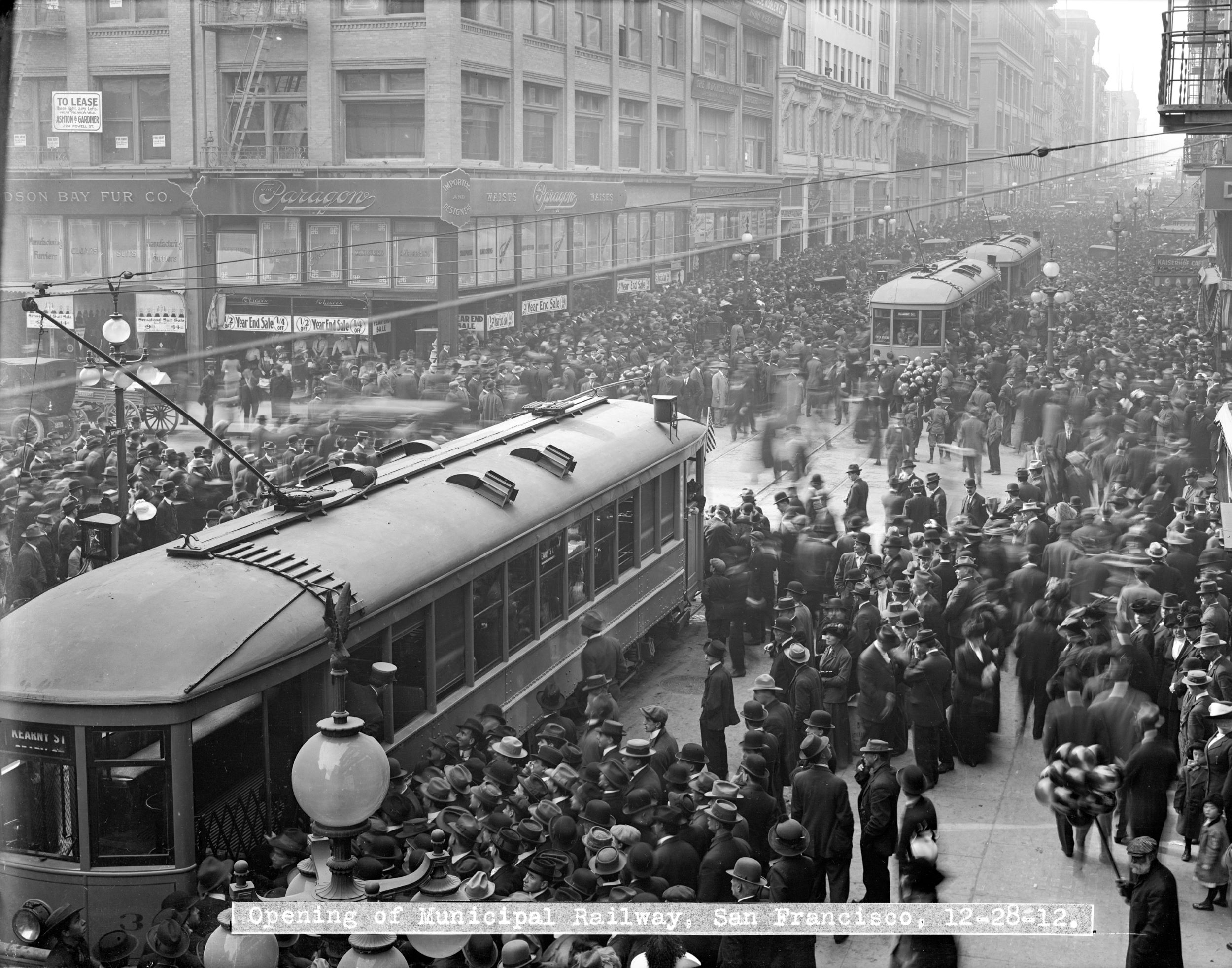 An archival image from 1912, showing streetcars with crowds swarming around them.
