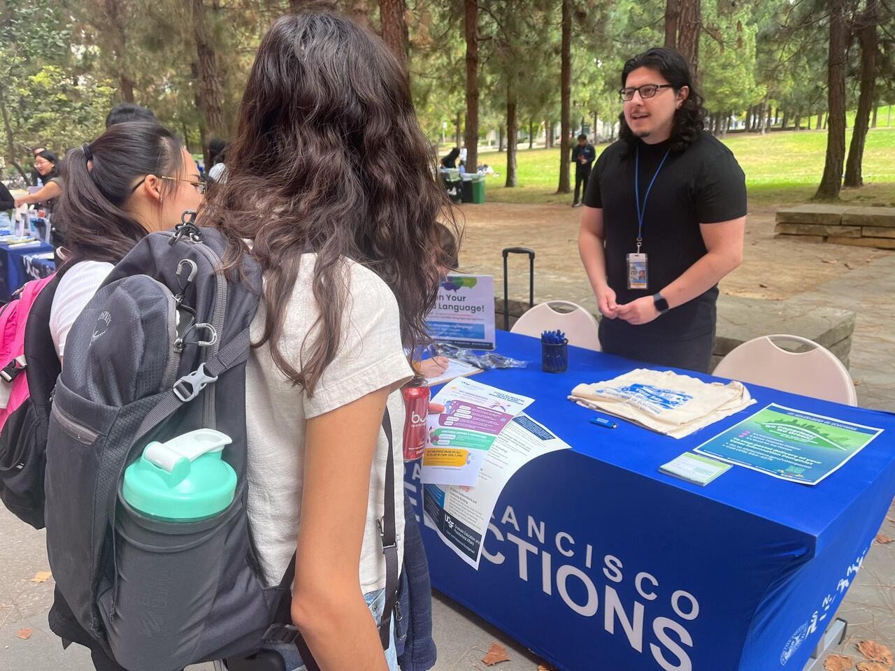 Elections staff member speaking with 2 university students about upcoming elections.