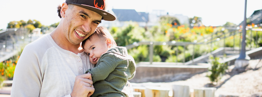 Child and father playing on swings in the park
