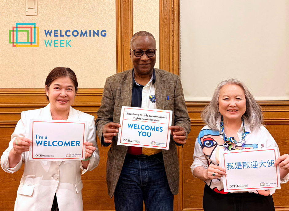 Three Immigrant Rights Commissioners smile and hold signs about Welcoming Week