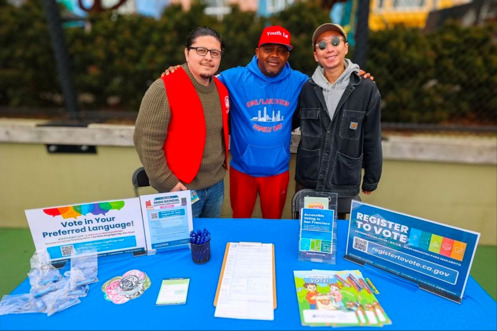 Elections staff posing for a photo with a representative from Youth 1st at One City Day outreach event.