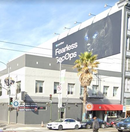 Billie Holiday Center is on the corner of the street. It is a two story building. It is a light grey and dark grey building with a red awning.