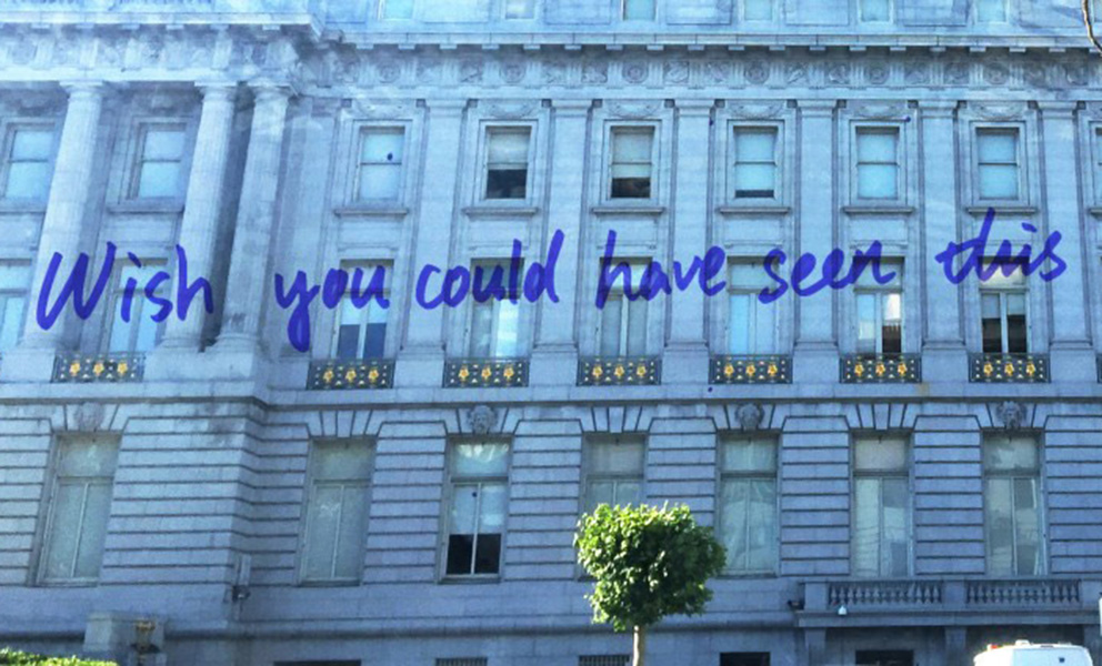 Historic stone building façade with columns and windows, overlaid with the handwritten text “Wish you could have seen this.”
