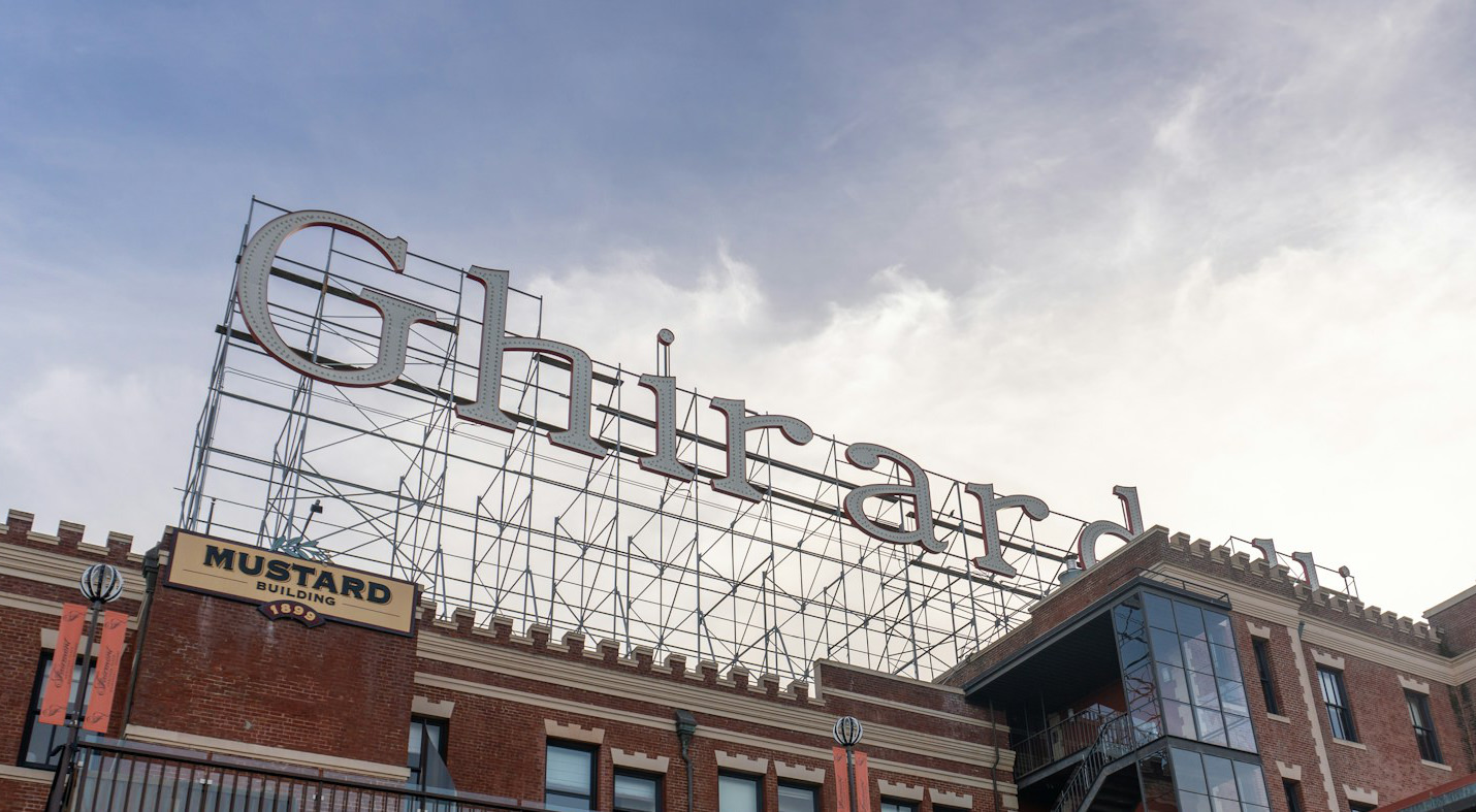 A view from below of a large, directly-illuminated roof sign supported by a large frame.