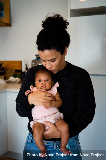 Mother holding her baby in the kitchen