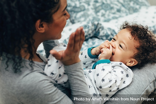 Smiling mother clapping and playing with young child