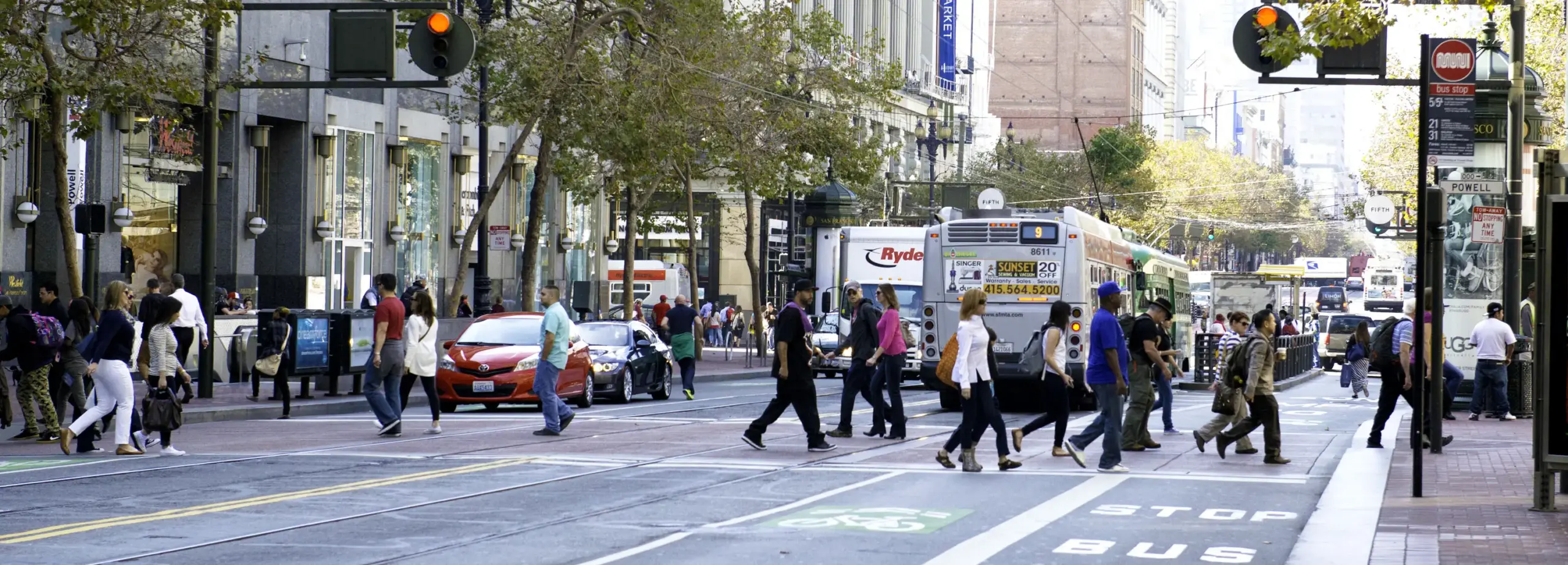 Pedestrians crossing market street with a Muni route 9 in the background.