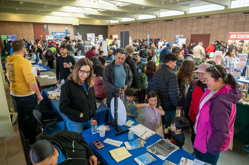 Large gathering of people visiting tables at resource fair for children in san francisco